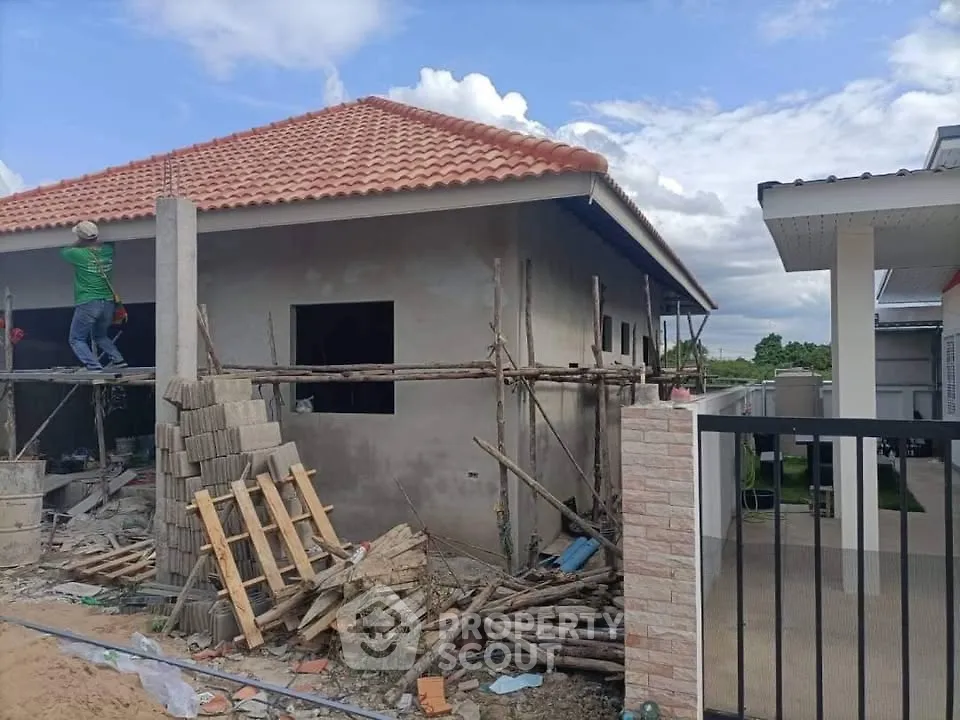 Under-construction house with red-tiled roof and scaffolding, showcasing potential for modern living.