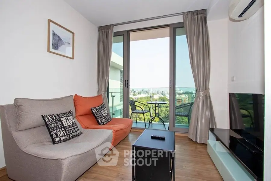 Modern living room with balcony view, stylish furniture, and natural light.