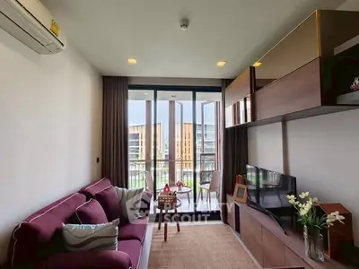 Modern living room with balcony view, stylish furniture, and ample natural light.