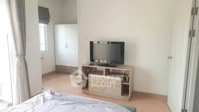 Cozy bedroom with modern TV stand and wardrobe, natural light from window.