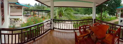 Spacious balcony with wooden furniture and lush garden view, perfect for relaxation.