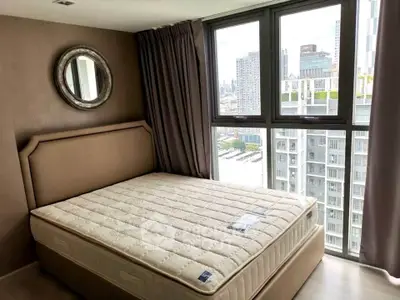 Modern bedroom with large window offering stunning city views in a high-rise apartment.