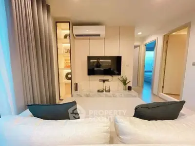 Modern living room with sleek design, featuring a wall-mounted TV, stylish shelving, and cozy seating area.