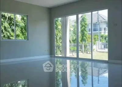 Spacious living room with large windows offering garden views in modern home.