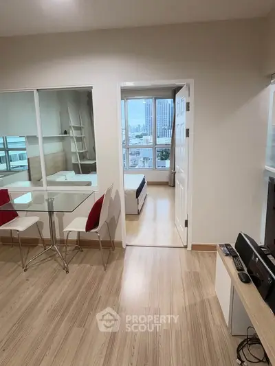 Modern apartment interior with open layout, featuring a dining area and a view into a cozy bedroom.