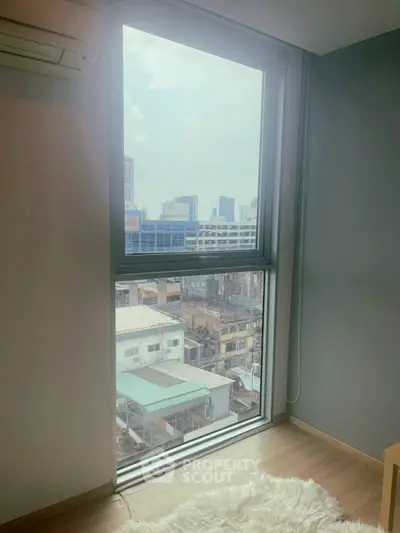 Bright room with large window offering stunning city view, perfect for urban living.