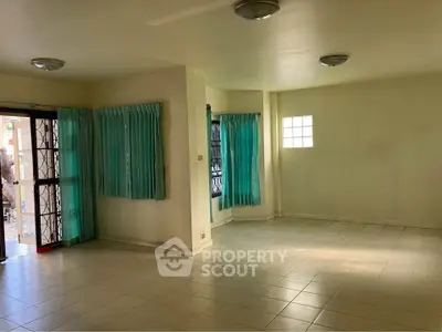 Spacious empty living room with natural light and tiled flooring