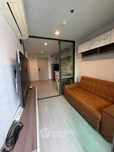 Modern living room with brown leather sofa and flat-screen TV, featuring sleek design and open layout.