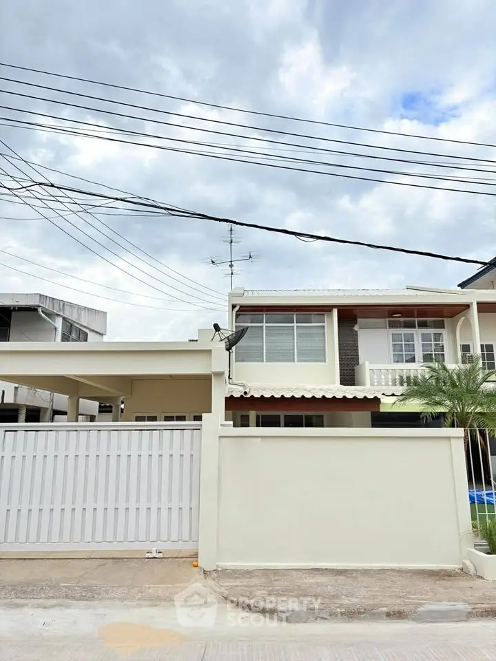 Charming two-story house with gated entrance and lush palm tree, perfect for family living.