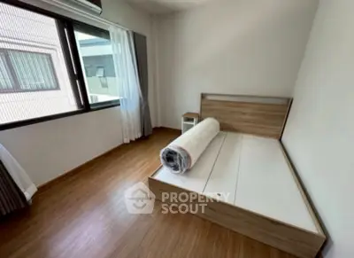 Spacious bedroom with large window and wooden flooring in modern apartment.