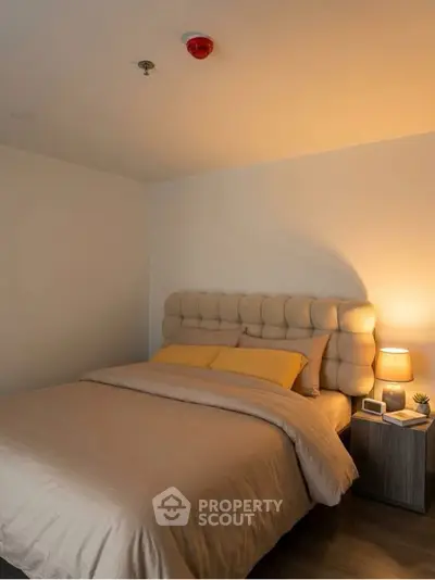Cozy bedroom with plush headboard and warm lighting, perfect for relaxation.
