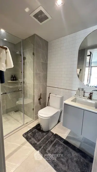 Modern bathroom with glass shower, sleek vanity, and contemporary fixtures.