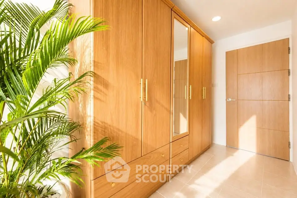 Spacious hallway with wooden wardrobe and indoor plant, showcasing elegant interior design.