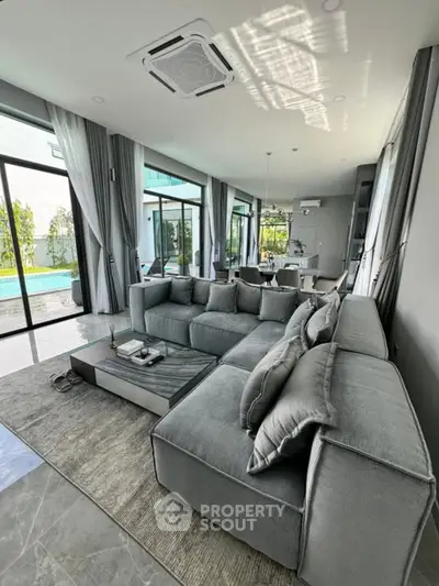 Luxurious modern living room with pool view and elegant gray sectional sofa.