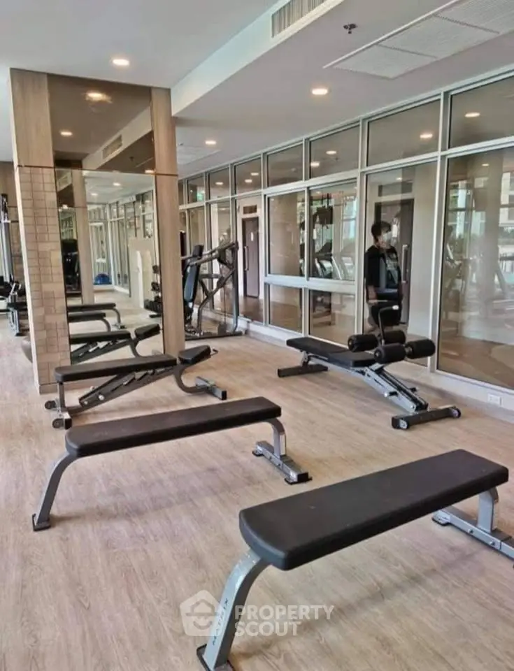 Modern gym with state-of-the-art equipment in a residential building, featuring sleek design and ample natural light.