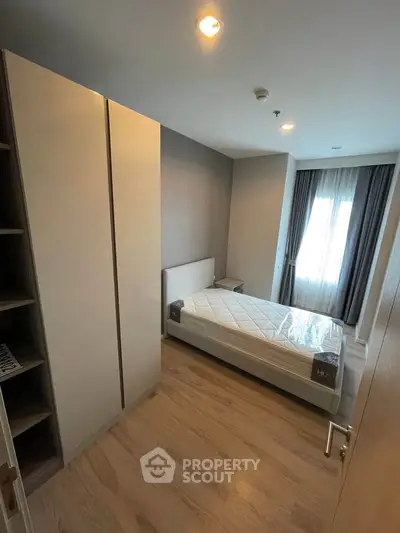 Modern bedroom with sleek wardrobe and natural light from large window.