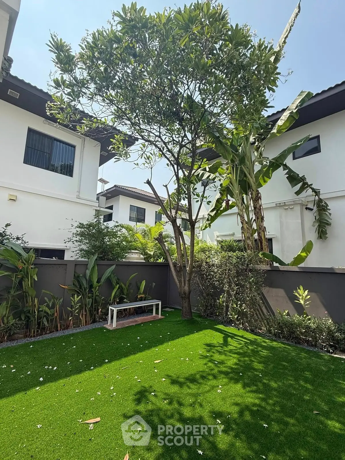Charming garden view with lush greenery and modern white houses, perfect for serene outdoor living.