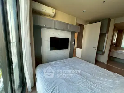 Modern bedroom with wall-mounted TV and large window offering natural light