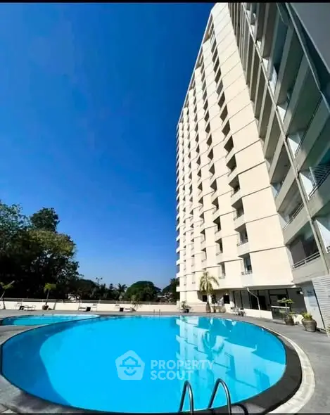 Luxurious high-rise building with stunning pool and clear blue sky view.