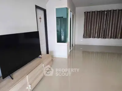 Spacious living room with modern TV setup and elegant curtains, perfect for relaxation.
