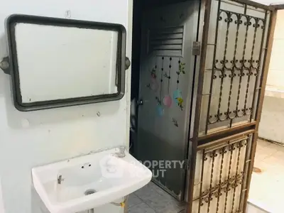 Compact bathroom with wall-mounted sink and decorative door in a real estate property.