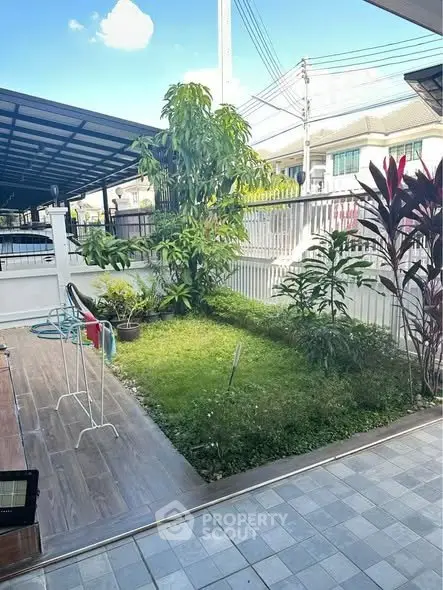 Charming garden view with lush greenery and tiled patio in a residential area.
