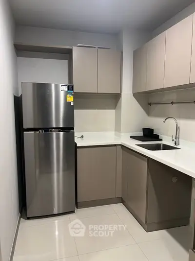 Modern kitchen with sleek cabinetry and stainless steel fridge in a compact layout.