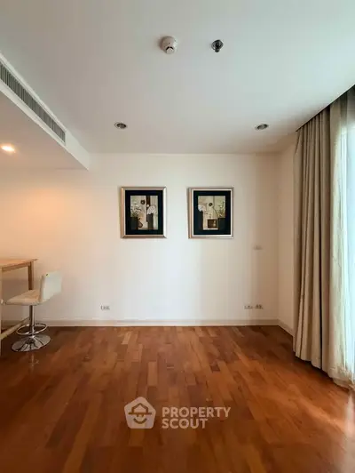 Spacious living room with wooden flooring and modern decor in a stylish apartment.