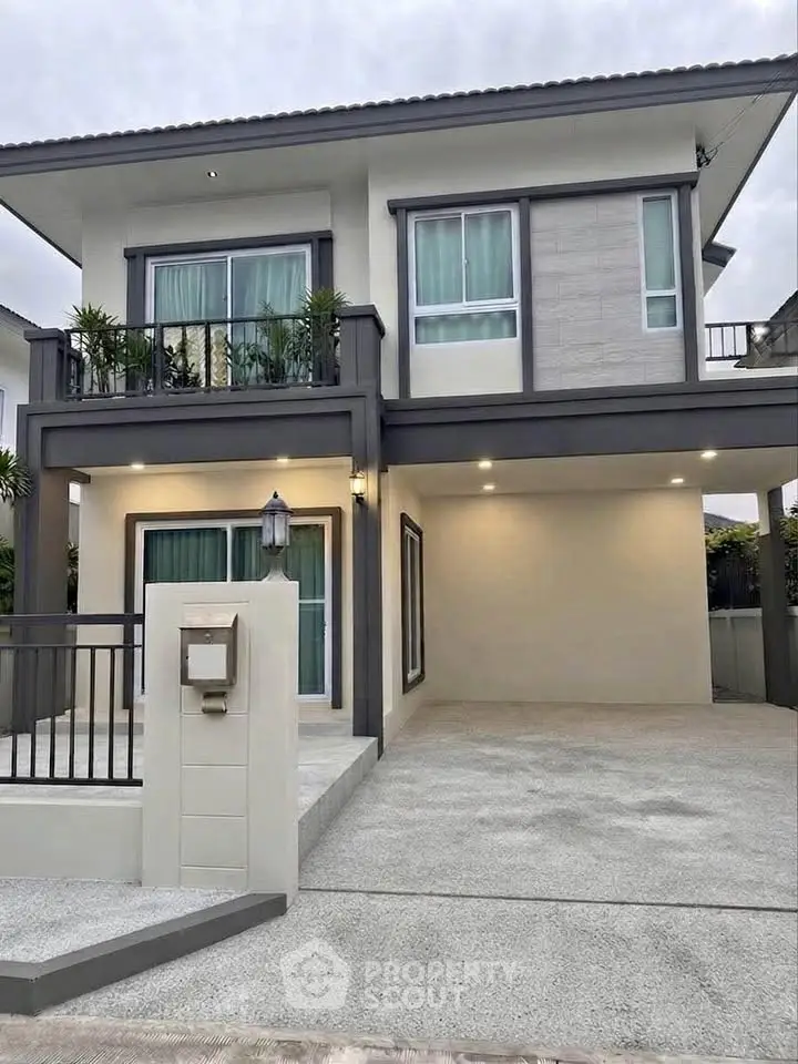 Modern two-story house with spacious driveway and balcony, featuring sleek design and large windows.