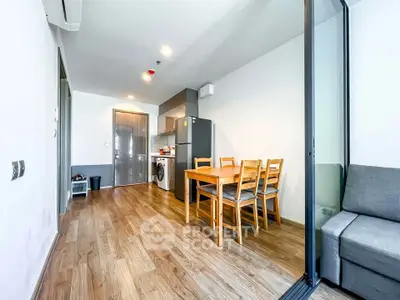 Modern apartment interior with wooden flooring, dining area, and kitchen appliances.