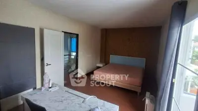 Spacious bedroom with modern decor and large window for natural light.