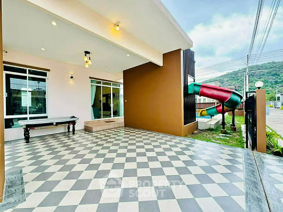 Spacious modern patio with checkered flooring and colorful slide, perfect for family entertainment.