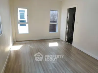 Spacious empty room with wooden flooring and natural light