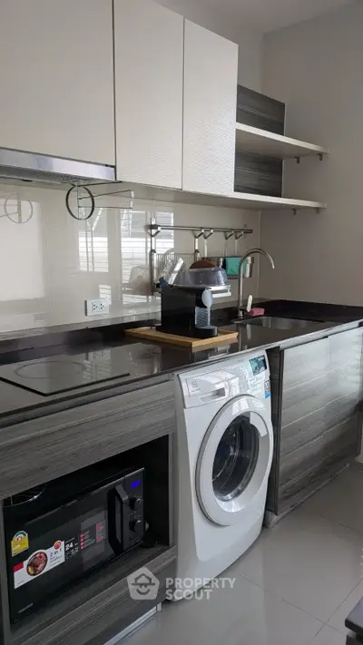 Modern kitchen with sleek cabinetry, washing machine, and built-in appliances in a stylish apartment.