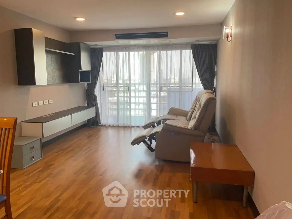 Spacious living room with modern recliner and large windows offering natural light.