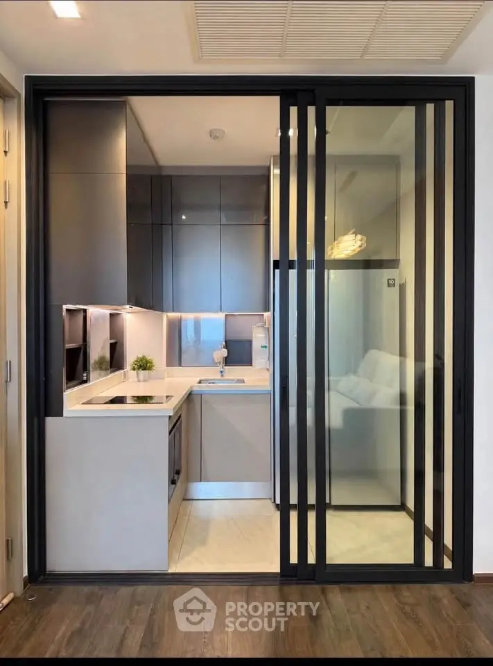Modern compact kitchen with sleek design and sliding glass doors in a stylish apartment.