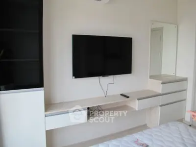 Modern bedroom with wall-mounted TV and sleek furniture design.