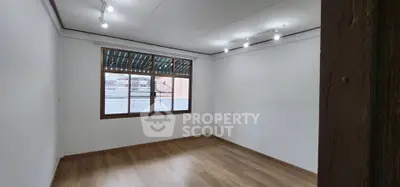 Spacious empty room with wooden flooring and large window