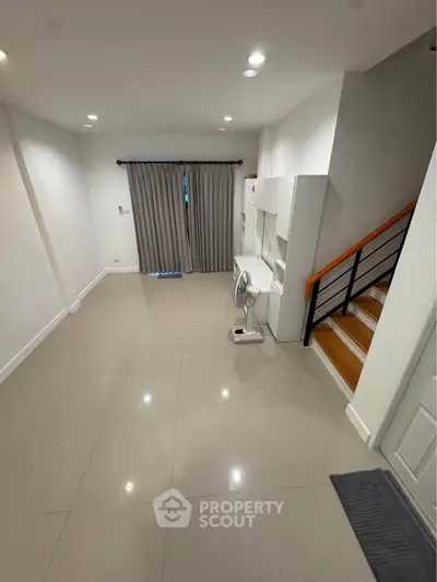 Spacious modern living room with sleek tile flooring and staircase