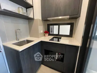 Modern compact kitchen with sleek dark cabinets and built-in appliances