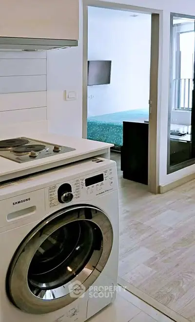Modern apartment interior with washing machine and view into bedroom