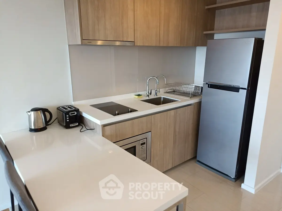 Modern kitchen with sleek appliances and wooden cabinetry in a compact layout.