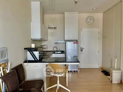 Modern compact kitchen with sleek cabinets and appliances in a cozy apartment setting.