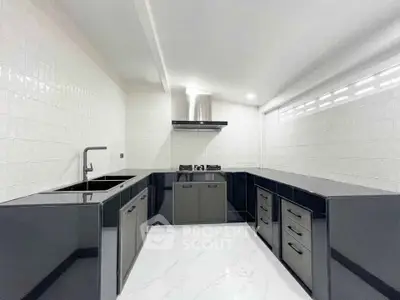 Sleek modern kitchen with black cabinetry and gas stove in a minimalist design.