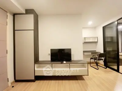 Modern living room with sleek furniture and wooden flooring, featuring a TV unit and study area.