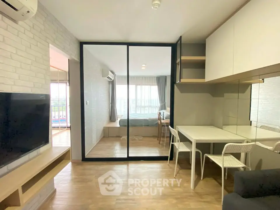 Modern apartment interior with open layout, featuring a cozy living area and a view into the bedroom.