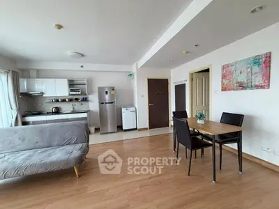 Spacious open-plan living room with modern kitchen and dining area, featuring sleek appliances and stylish decor.