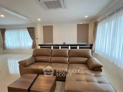 Spacious living room with modern leather sofa and large windows for natural light.