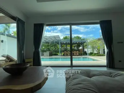 Luxurious living room with pool view and lush garden, perfect for relaxation and entertaining.