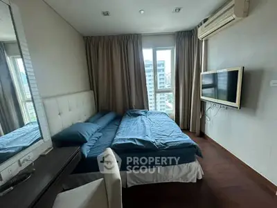 Modern bedroom with large window and wall-mounted TV in a high-rise apartment.